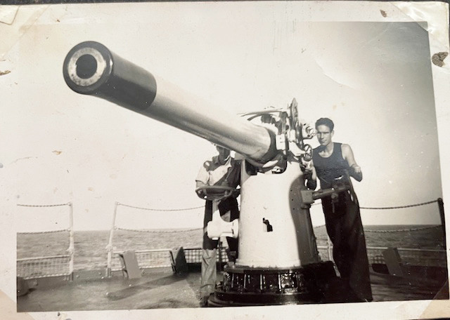 Gordon (on the left, obscured by the gun) on the deck in his role as a gunner during World War II.
