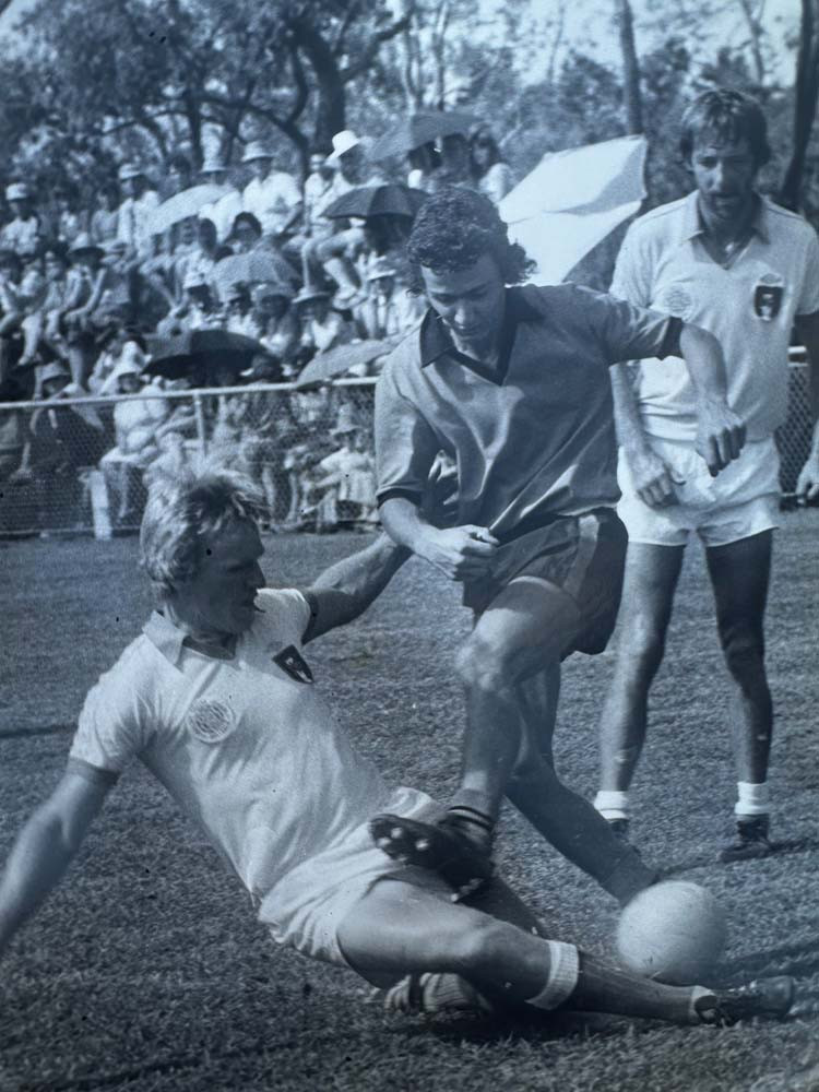 left: Peter Tokisi tackling Loui Serafini during a state league match.