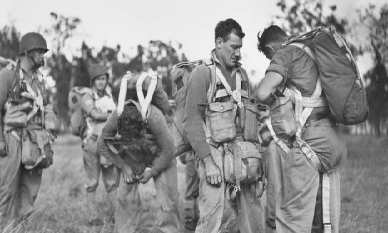 Jumpmasters of the 1st parachute battalion assist each other to attach their equipment during preparations for jumping operations from 700 feet. PHOTOS: AUSTRALIAN WAR MEMORIAL.