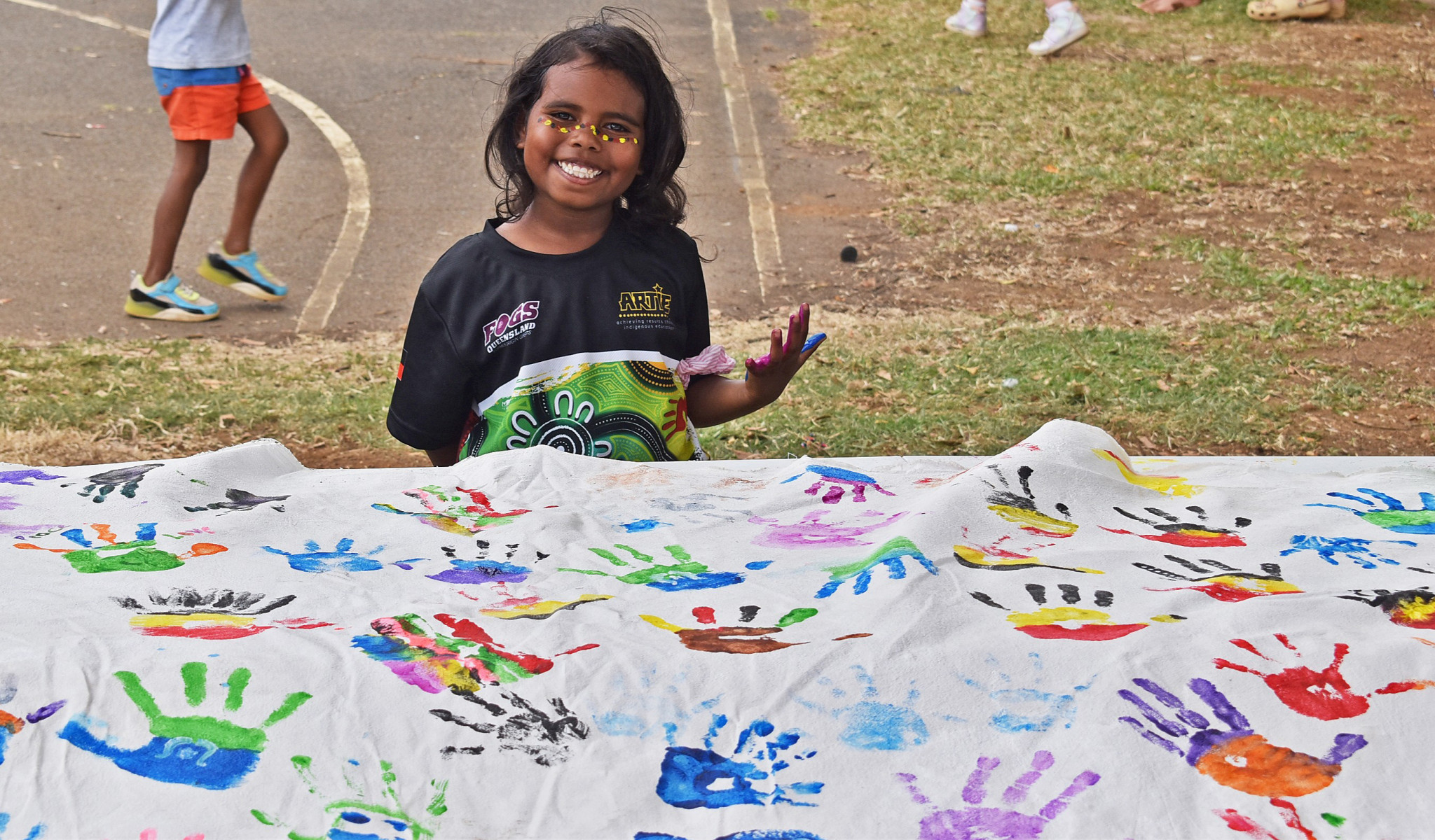 Kamiya, 6, putting her hand imprint on the NAIDOC artwork.