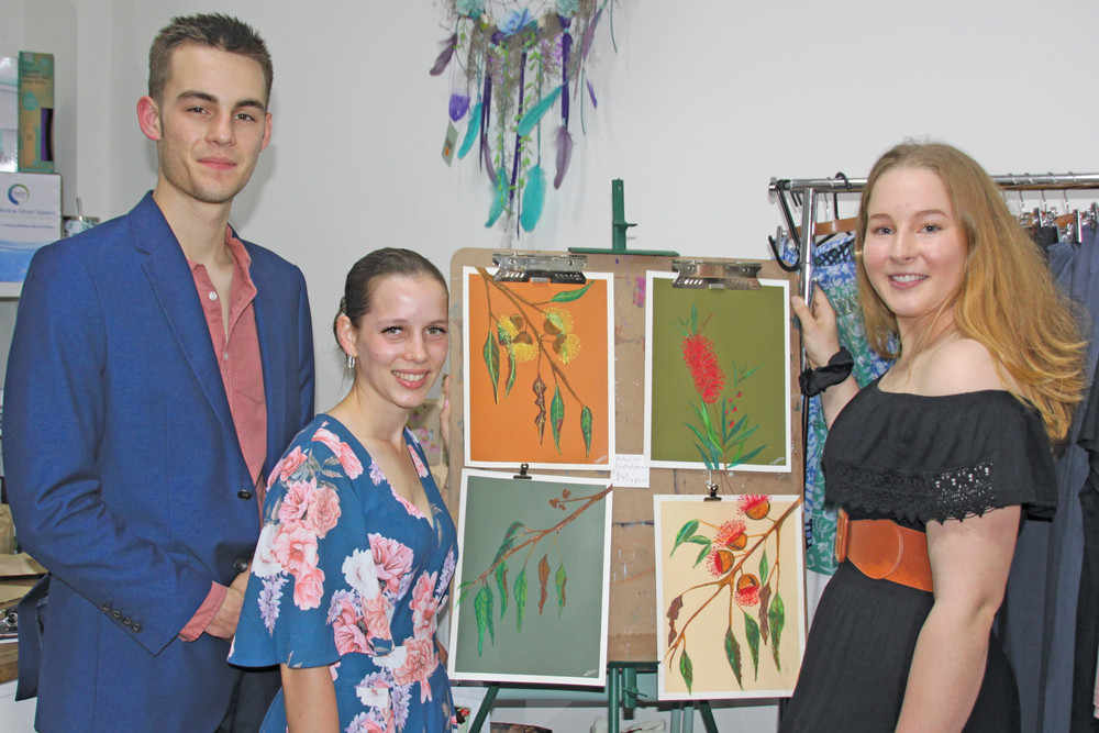 Artist Abbey Wilson (R), shows guests Toby and Zoe Watson an example of her work.