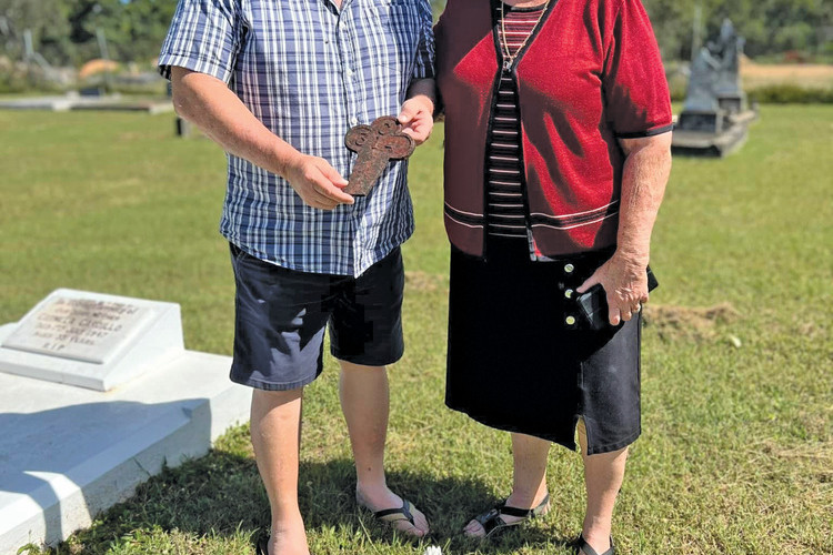 After hours of research, Nasem Tahir and Dita Carusi standing at the burial plot of Xhemal Isuf with the flowers they placed on the grave site.