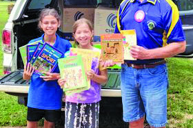 Atherton Lions Club president Neil Clarke with Walkamin State School students and their massive donations of books to the Atherton Lions Kids Literacy Project