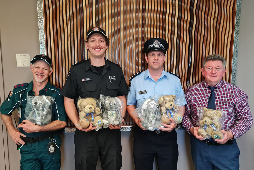 Paramedic Neville Condon, Fire Fighter Jared Hohns and Acting Inspector Kyell Palmer receiving Care Bears from Mareeba Lion Tom Braes.