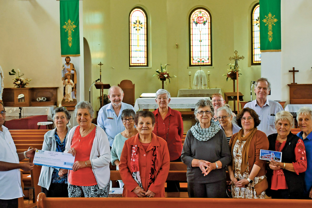 Atherton Parish Catholic Ladies treasurer Josie Raso gives $10,000 to Father Mathew Kochuveettil for the Restoration Appeal. The money was raised from old-fashioned catering, cake stalls and lamingtons.