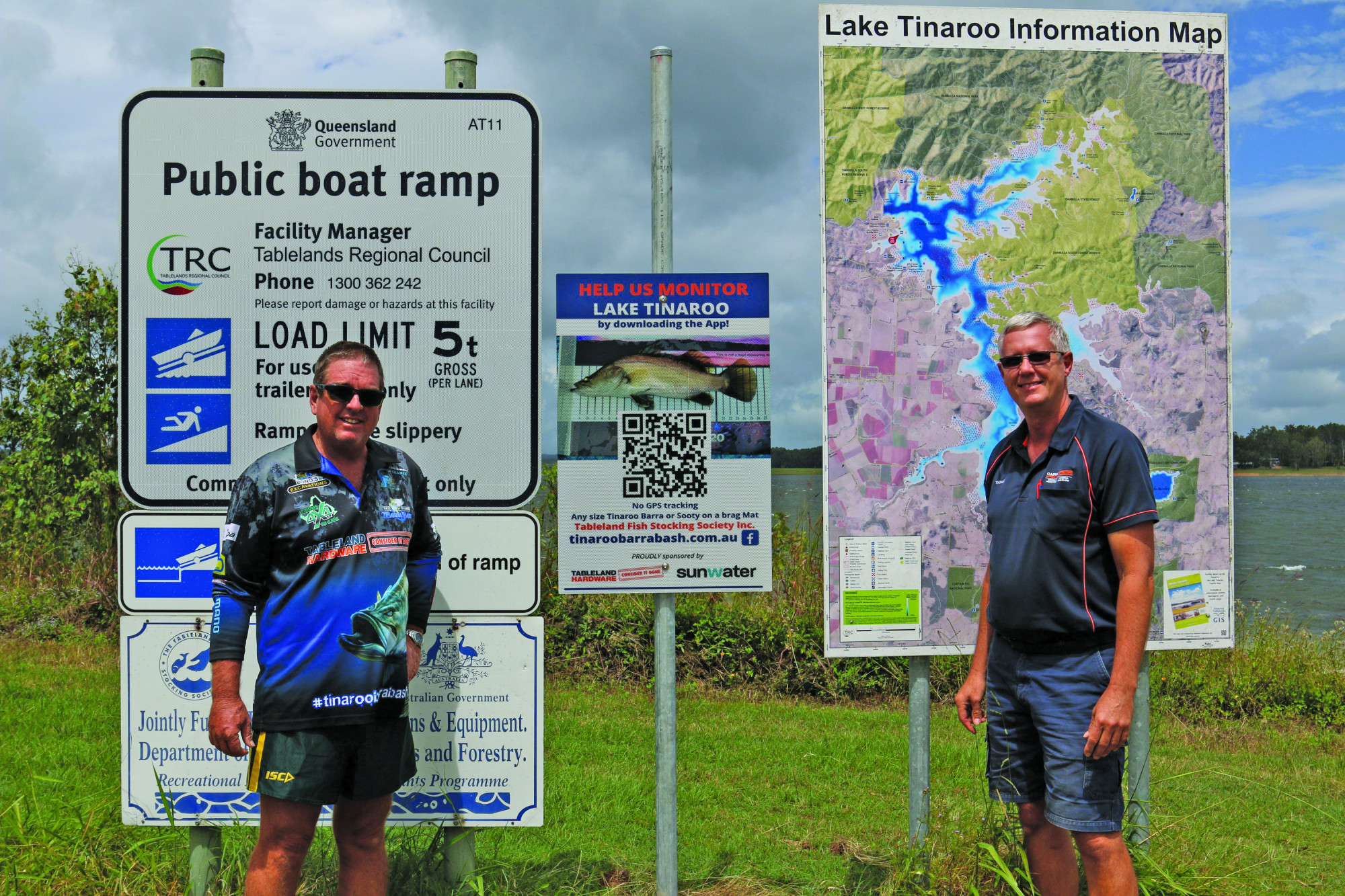 Ian Leighton and Thomas Tiepner with one of the new signs installed by the Tableland Fish Stocking Society at Lake Tinaroo.