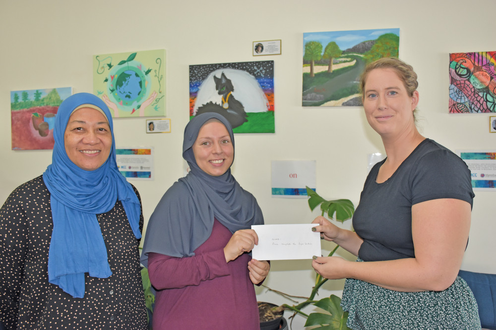 Mareeba Islamic Society members Nur Bajramovic and Allma Murat presenting Mareeba Community Centre front office coordinator Ashlee Wilkinson with the $1000 cheque.