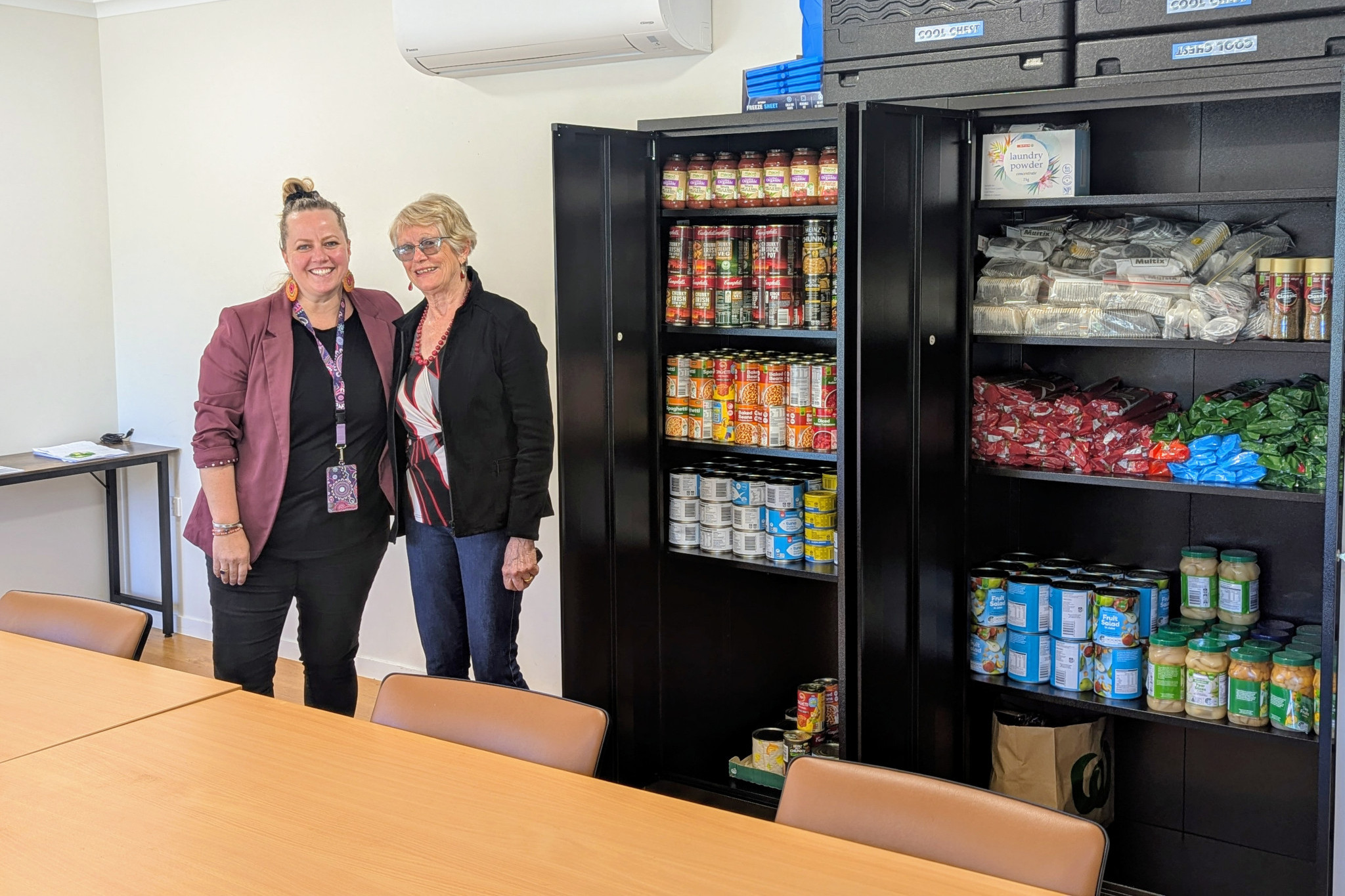 ECHO Neighbourhood House Manager Donna Cifuentes (left) and Tropical Tablelands Soroptimist Club member Sylvia Edwards pictured with one of the cupboards storing food and toiletry items purchased with donated funds.