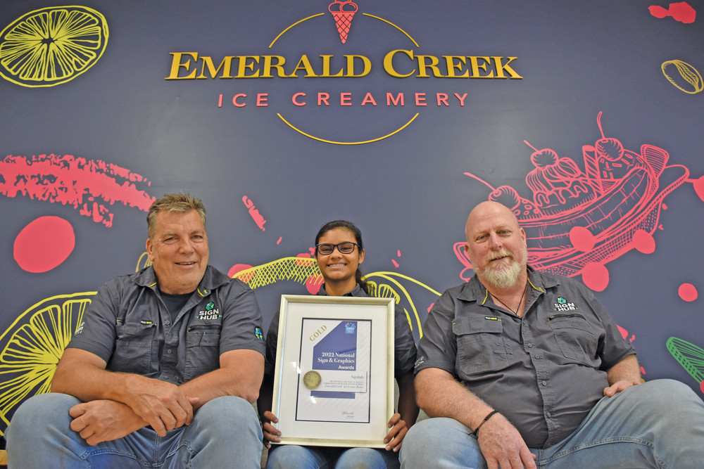 Signhub Atherton owner Bob Ramsay with signwriter apprentice Mia Caulfield and signwriter Andy Lowe in front of the award-winning mural at the Emerald Creek Ice Creamery.