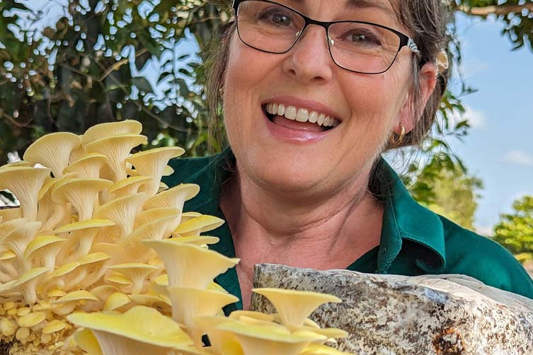 Shelley Berry-Porter with some Golden Oyster mushrooms and below, a Shiitake mushroom growing out of a substrate block.