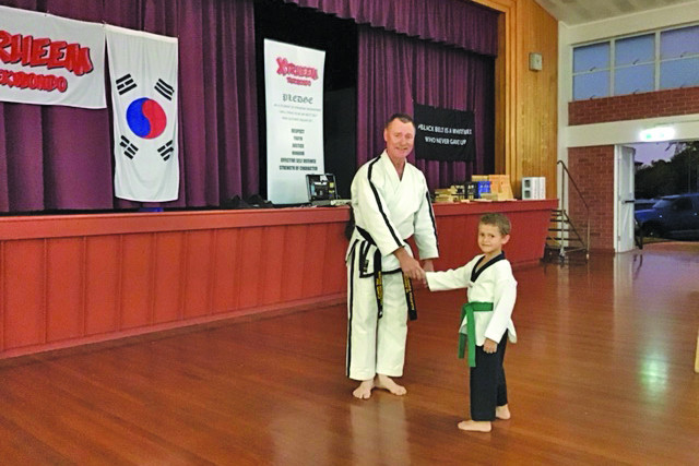 Seven year old Mac Sivyer receiving his 6th grade green belt from master Phil Quayle.