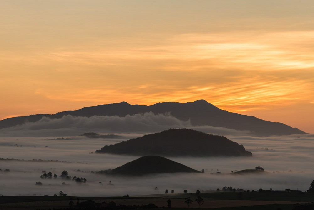 The heart of the Atherton Tablelands at dawn, with Mt Bartle Frere (The Rainmaker, Choorichillum in Ngadjon-jii, Queensland’s highest mountain), Mt Quincan (Australia’s most recently active volcano) and one of the Seven Sisters. Photographer: Jürgen Freund.