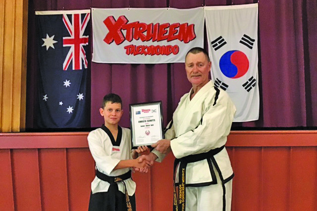 Christo Schutte being presented with his junior black belt certificate by master instructor Phil Quayle following his promotion at the Xtrheem Taekwondo winter gradings.