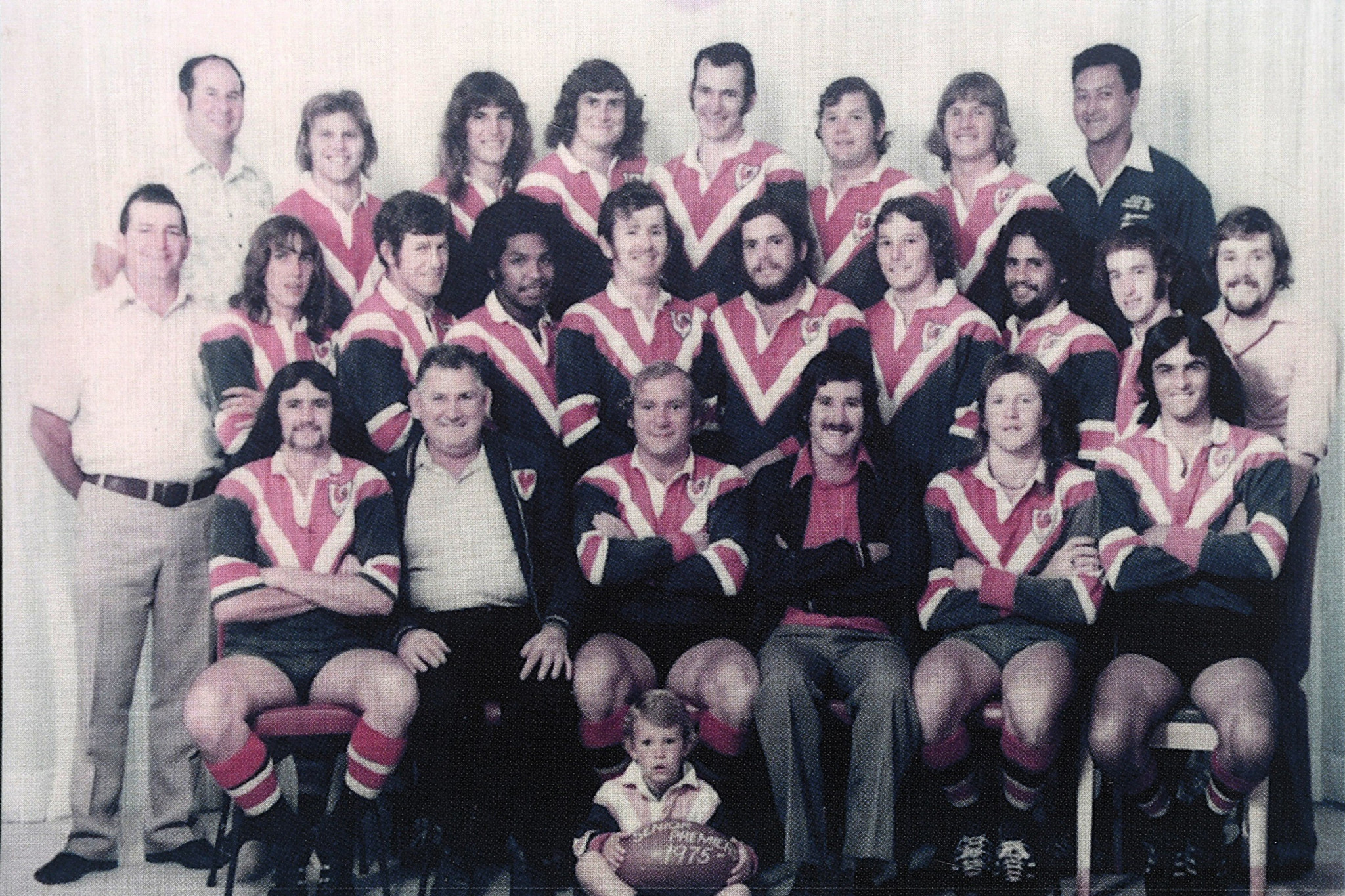 The 1975 Atherton A Grade Eacham Rugby League Premiers. Back Row: Eric Richardson (assistant manager), Bill Thorne, John Marnane, Darryl Denney, Mick Fleming, Barry Petrie, David Arbouin, Colin Lee Long (masseur). Middle Row: Ted DeBondi (manager), Savoy Brown, Sid Bryden, Christo Benjamin, Ron Giveen, Jeff Moss, Sam De Tournouer, Doug Stewart, Ian Beattie, Chris Conway (physio). Front Row: Peter Hodge, Les McElligott (vice-president), Graham Bevan (captain/coach), Brian Geraghty (president), Len Standen, Steve Evans. Mascot: Jason Petrie. Absent: Tom Masters.